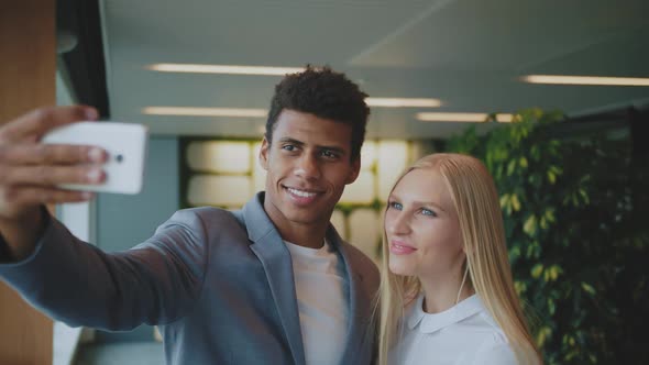 Laughing Diverse Coworkers Taking Selfie in Office. Cheerful Black Man with Laughing Blond Woman
