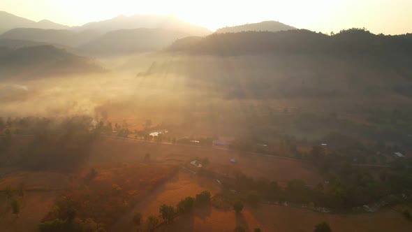 Aerial view over villages and barren fields in countryside during sunrise