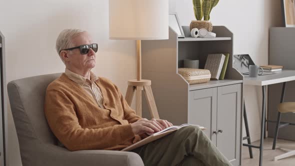 Blind Senior Man Reading Braille Book at Home