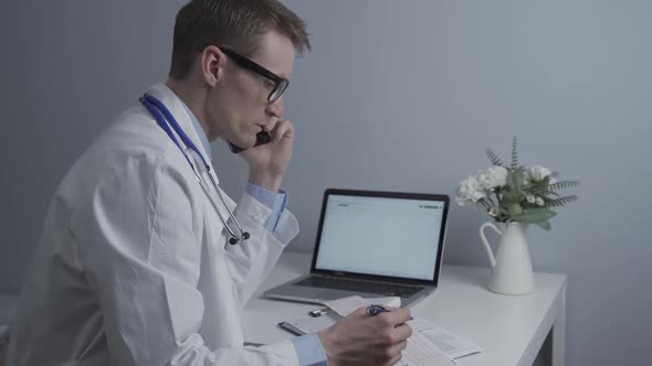 Cardiologist Checking Cardiogram and Consulting Patient on Phone