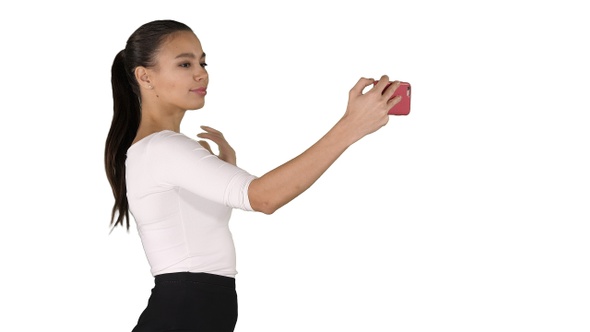 Pretty girl taking a selfie and walking on white background.