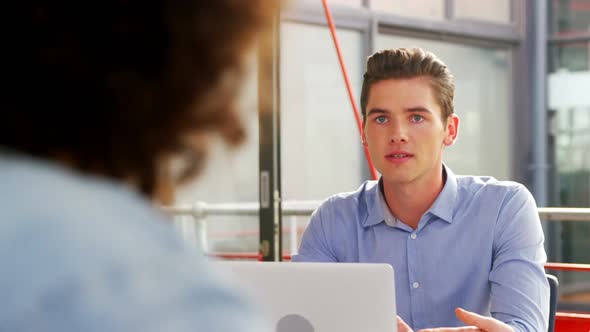 Business executives discussing over laptop in meeting