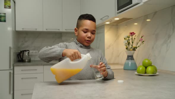 Handsome Black Boy Pouring Glass of Juice Drinking It Indoors