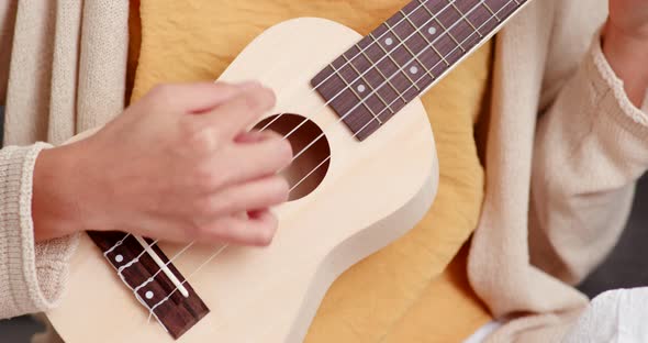 Woman play ukulele at home