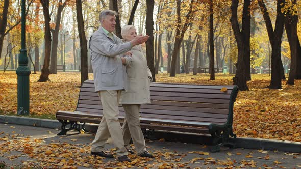 Elderly Married Couple Walking in Autumn Park Old Woman Holding Husband Hand Enjoy Conversation