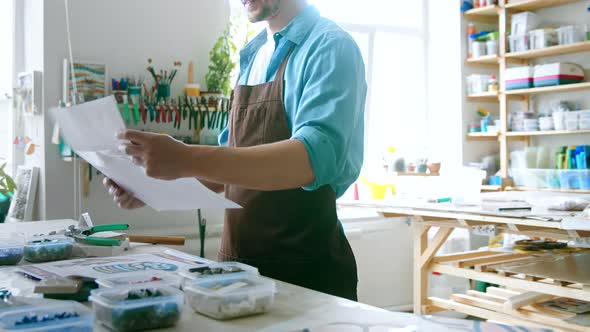 Young master in uniform looking at art sketches on the table