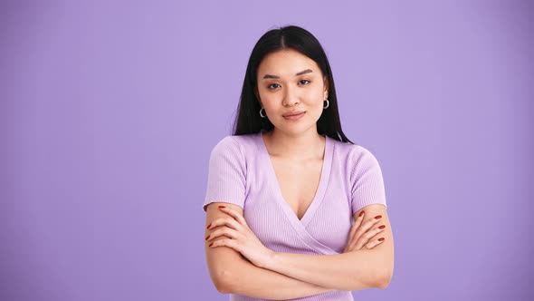 Handsome Asian brunette woman wearing purple t-shirt positively shaking her head