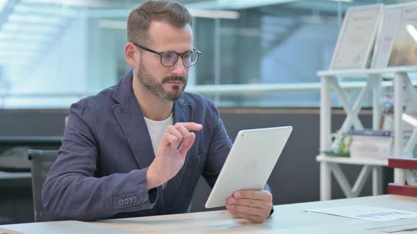 Middle Aged Businessman Celebrating Success on Tablet in Office