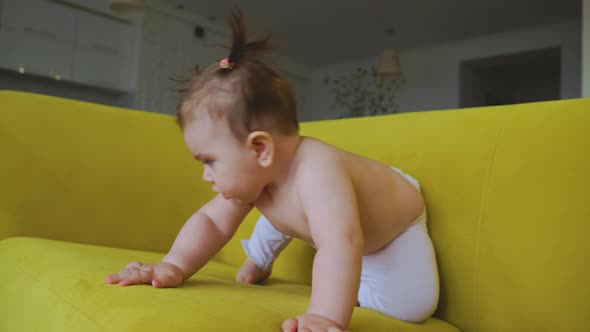 Cute Baby Girl on the Yellow Sofa at Home in the Living Room