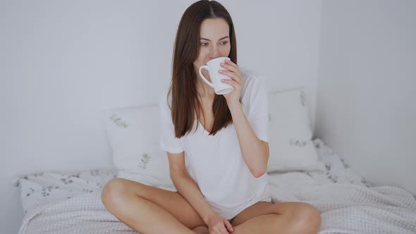 Calm Inspired Woman Having Hot Drink on Bed in Morning