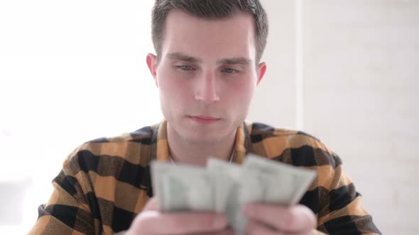 Young Man Counting Dollar Paper Currency
