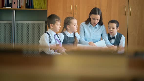 Elementary School Pupil and Teacher Discussing Picture with Classmates