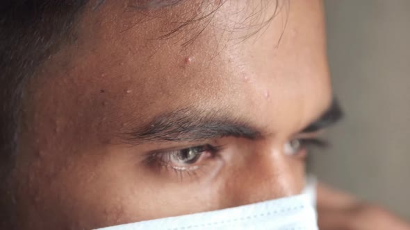 Young Asian Man Putting Surgical Face Mask Indoor