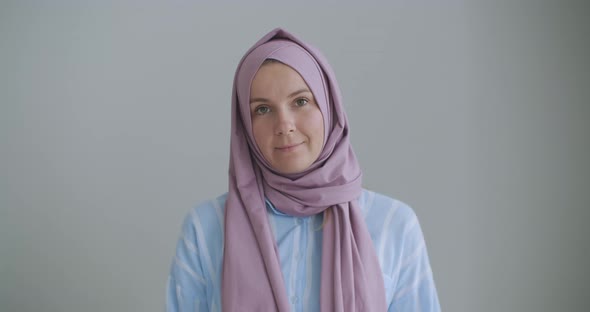 Looking at the Camera and Nodding Her Head, a Muslim Woman in a Hijab Is Talking on a Video Link and