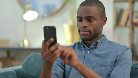 Young African Man Using Smartphone at Home 