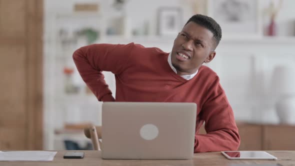 African Man having Back Pain while using Laptop in Office