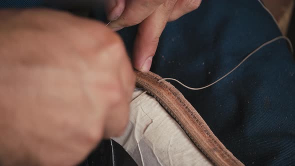 Close Up Shoemaker's Hands Stitching Shoe with Awl and Thread