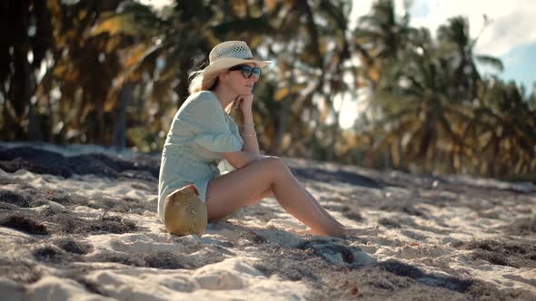 Girl In Bikini Sitting On Sand.Beautyful Woman On Tropical Island.Blonde Travel Girl Relaxing On Sea
