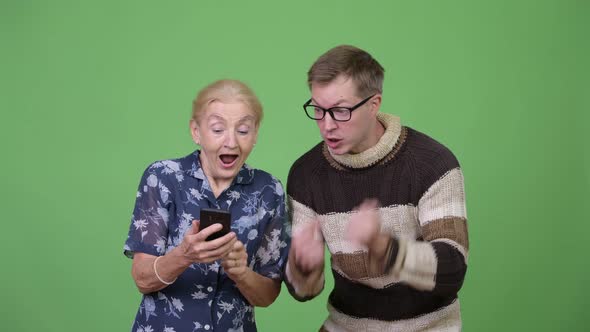 Happy Grandmother and Grandson Using Phone Then Giving Thumbs Up Together