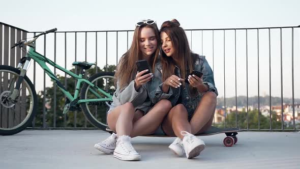 Girlfriends Sitting on the Skateboard and Having fun During Watching Photos