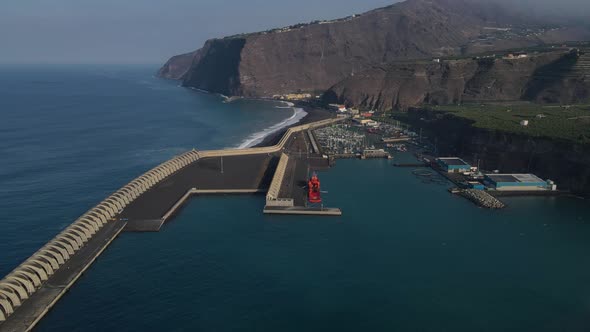 Drone flying over Tazacorte harbor and volcanic black beach, La Palma island. Aerial forward.