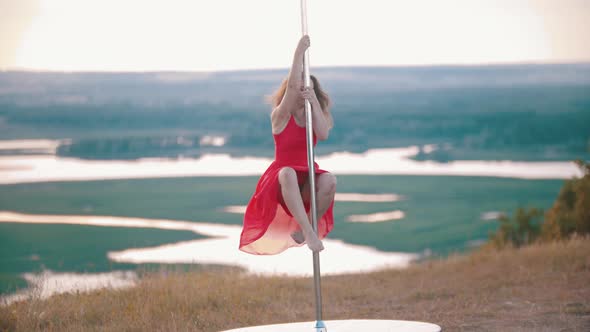 Young Woman in Pink Dress Dancing on the Pole Outdoors