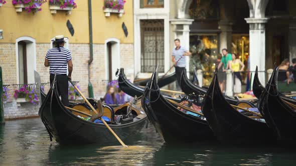 Handsome gondoliers entertaining tourists, giving ride around Venice sights