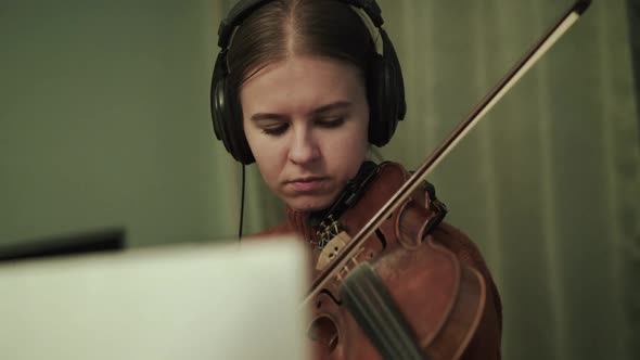 Female Artist with Headphones Rehearsing the Melody with Violin Under Mentorship