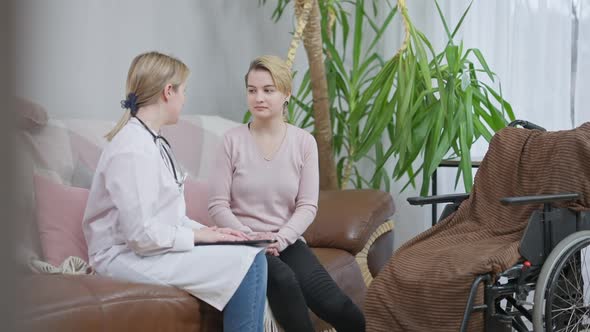 Portrait of Smiling Happy Disabled Young Woman Consulting Professional Doctor at Home and Shaking