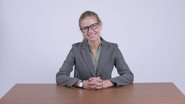 Young Happy Blonde Businesswoman Smiling and Sitting Behind Desk