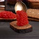 red caviar spills out of a spoon on a piece of rye bread - VideoHive Item for Sale
