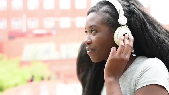 Portrait of young beautiful afro woman listening music with smart phone
