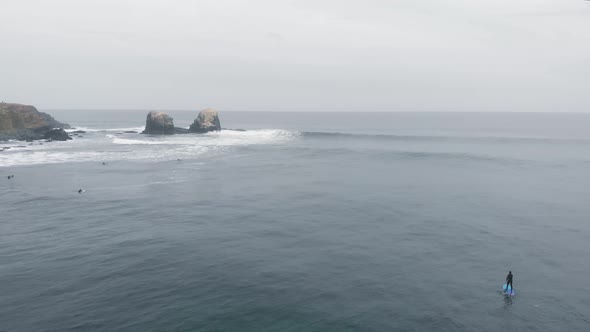 Aerial reveal of person paddle on a cloudy day at the Sea, Pichilemu, Chile-4K