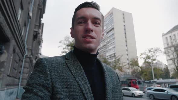 Smiling Young Business Man Making Selfie Video Call While Walking Outdoor at City Street