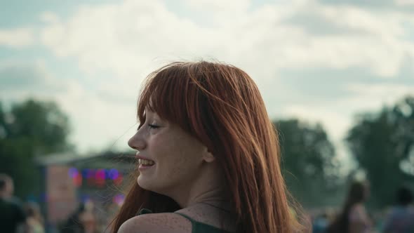 Camera tracking ginger haired smiling young caucasian woman at music festival. Shot with RED helium