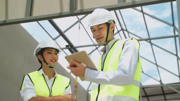 Asian colleague workers people wearing protective safety helmet and working onsite of architecture.