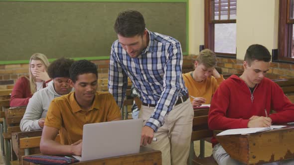 Teacher helping a teenager in high school class