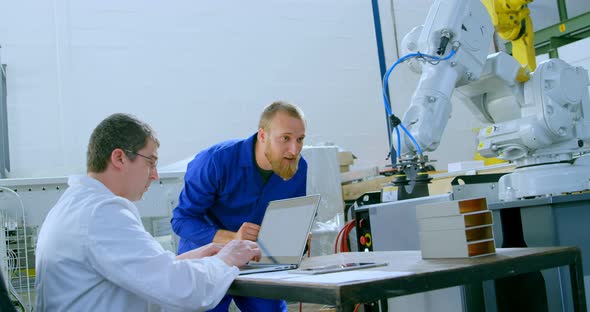 Robotic engineers examine robotic machine in warehouse 4k