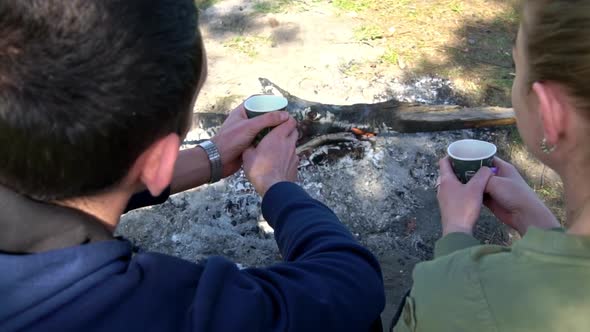 Couple in Love Sits Near a Dying Fire with Coffee