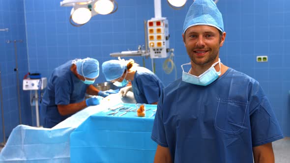 Surgeon looking at camera while colleagues performing operation