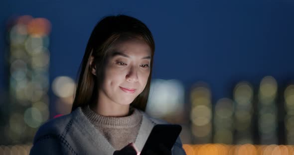 Woman use of mobile phone in city at night