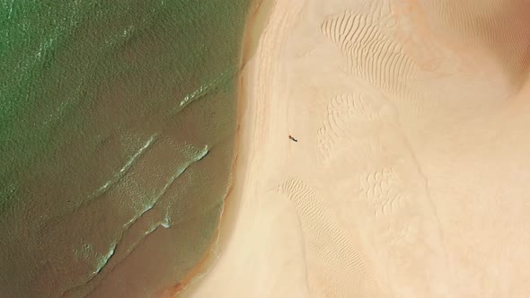 A Jogger Runs Along Pristine White Sand Surrounded with Turquoise Waters