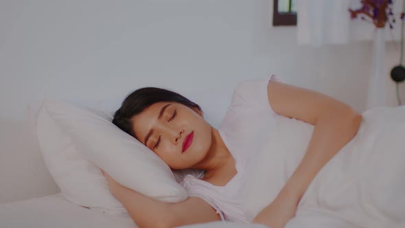 Beautiful Attractive Asian woman sleep and sweet dream lying on bed in cozy bedroom