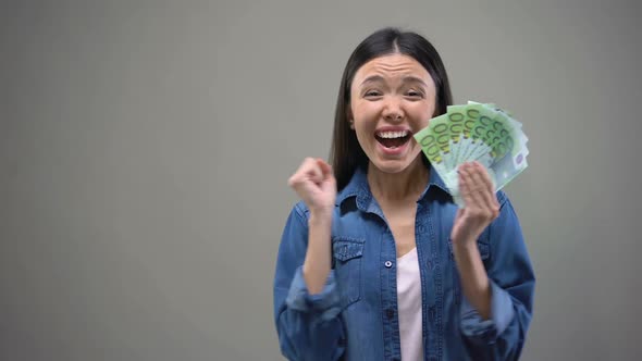 Excited Asian Woman Showing Euro Banknotes on Camera, Lottery Winner, Fortune