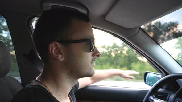 Profile of Handsome Man in Sunglasses Driving Car at Countryside