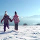 Charming Kids in Outwear Running on Snowy Terrain with Beautiful Mountains on Background in Sunshine - VideoHive Item for Sale