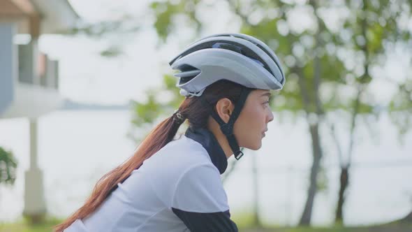 Asian young beautiful woman in sportswear riding bicycle for health in the evening in public park.