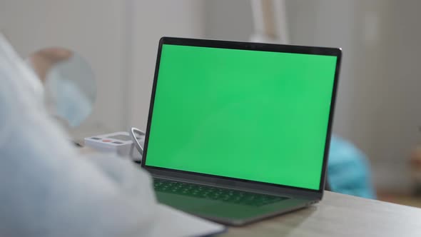 Closeup of Chromakey Laptop with Unrecognizable Doctor Sitting at Table Talking