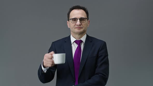 Handsome Confident Middle Aged Man Holding Cup of Coffee and Looks at Camera