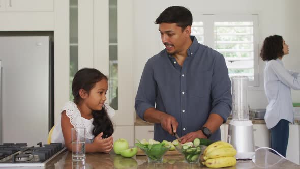 Hispanic father teaching smiling daughter cooking in kitchen